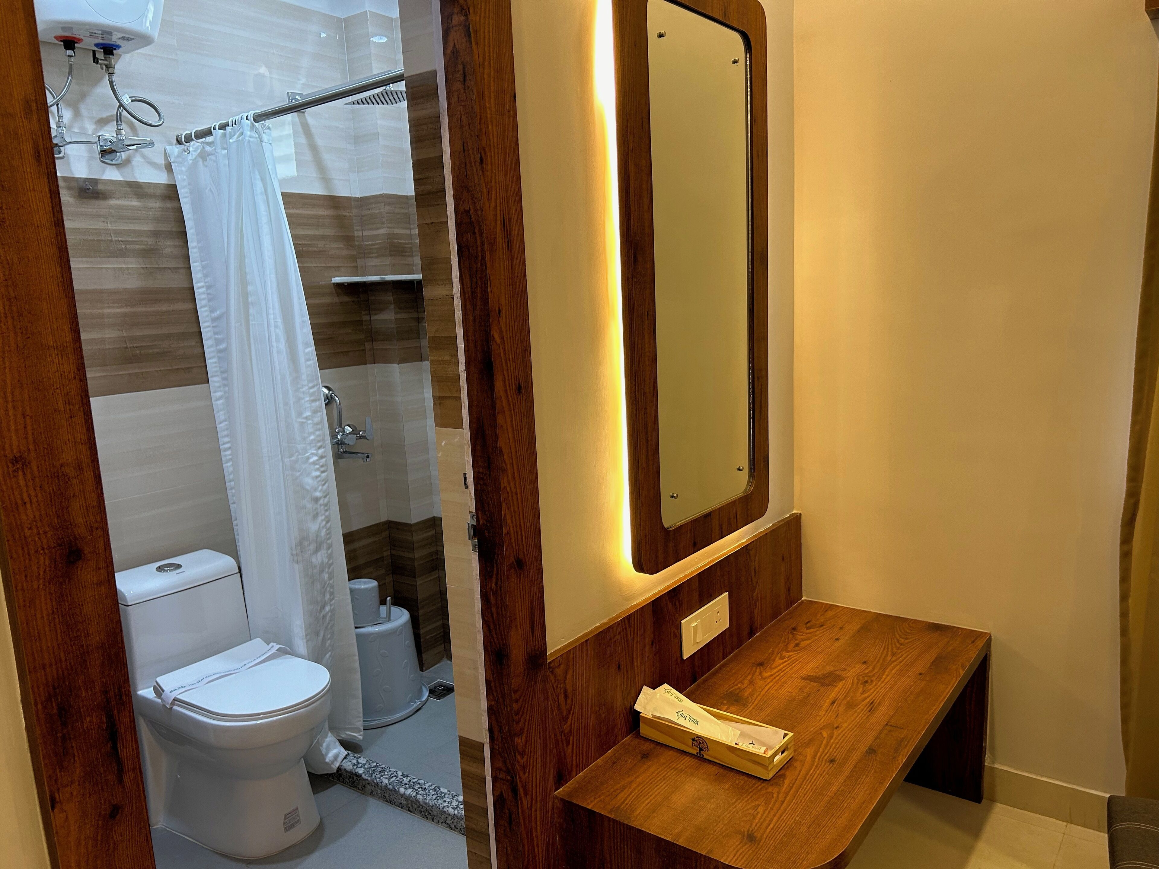 A bathroom with a toilet, shower, and a wooden vanity with a mirror.