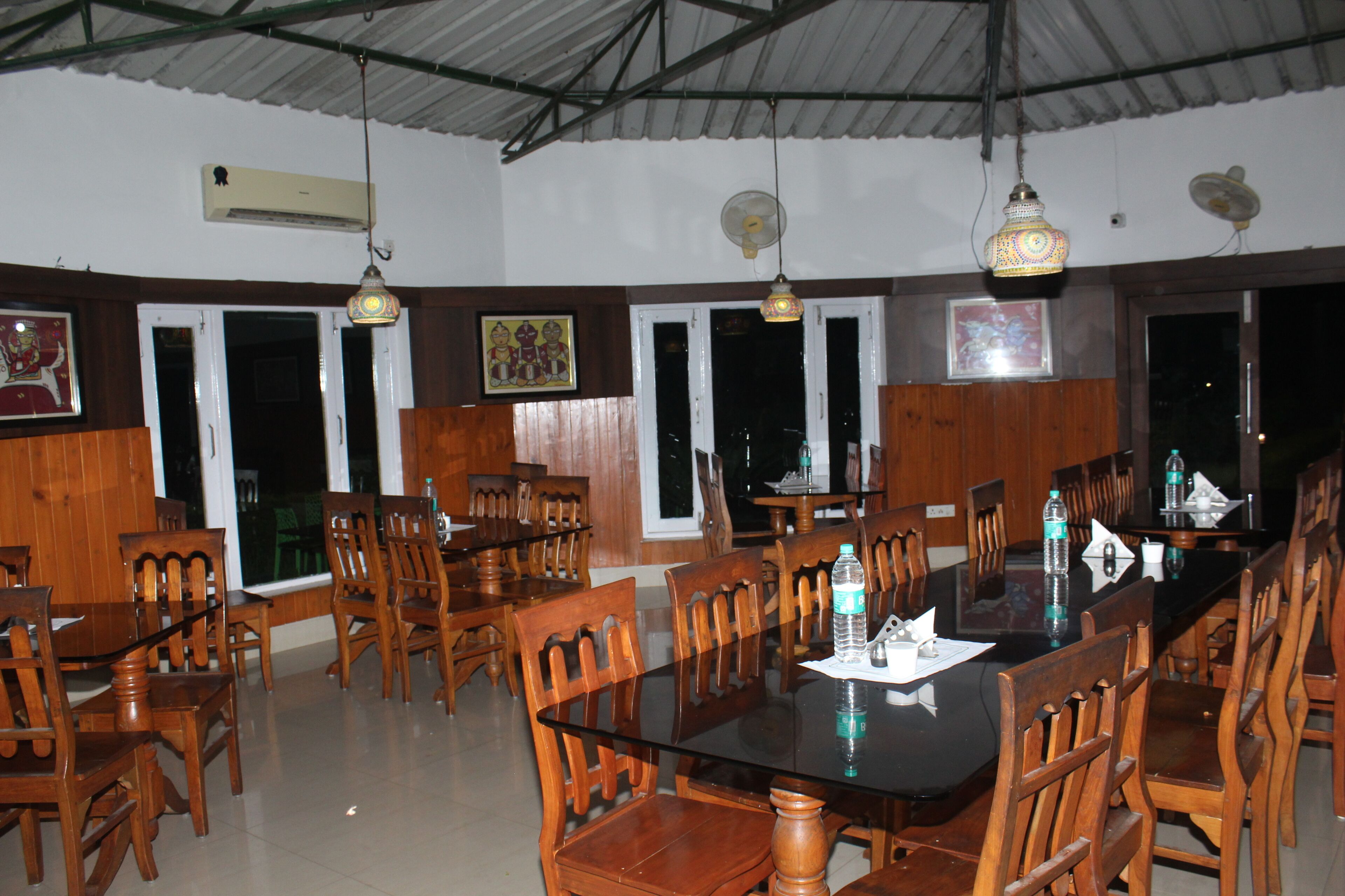 Um restaurante com mobiliário de madeira, janelas amplas e luminárias pendentes.