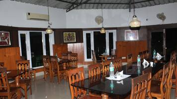 Um restaurante com mobiliário de madeira, janelas amplas e luminárias pendentes.