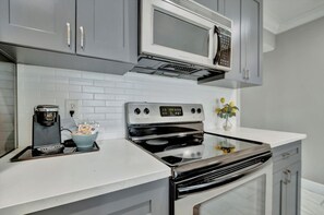 A kitchen with a microwave, stove, and coffee maker.