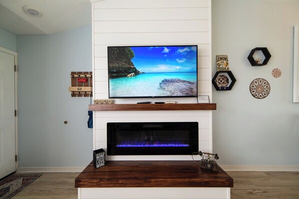 A living room with a flat-screen TV mounted above a fireplace, a mounted telephone, and decorative wall art.