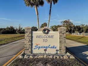Letrero de bienvenida para SpringLake, con borde de piedra y un arreglo floral en la parte superior.