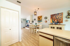 A kitchen with a dining area, wooden flooring, and a white door.