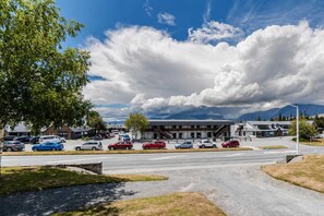 A parking lot with multiple cars, a building with a modern design, and a mountain range in the background. - Starlight Suite | Tekapo 1BR + Lake Walk (Lake Tekapo)