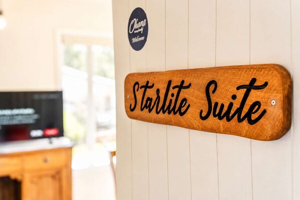 A wooden sign with 'Starlite Suite' written on it, mounted on a wall with a 'Welcome' sign above.