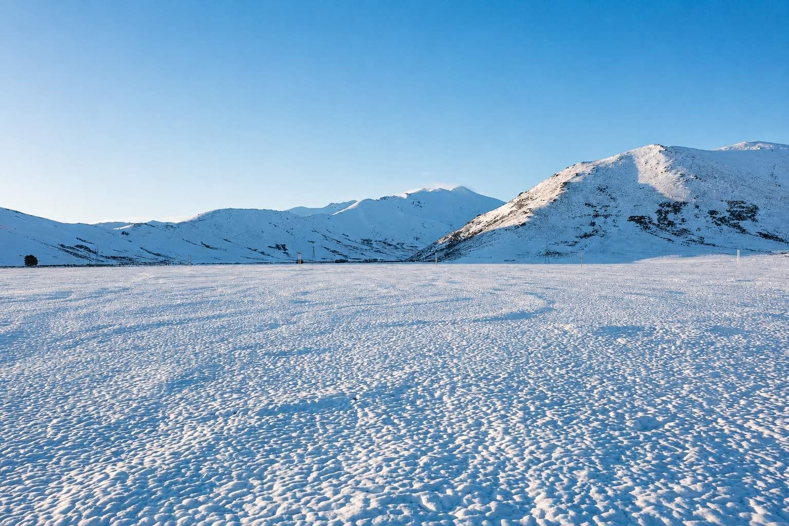 A snowy landscape with a mountain range in the background.