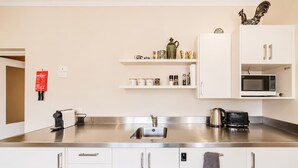 A modern kitchen with stainless steel countertops, a coffee machine, a kettle, a microwave, and storage cabinets. - Starlight Suite | Tekapo 1BR + Lake Walk (Lake Tekapo)