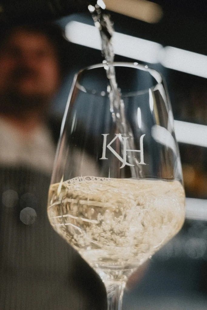 Un vaso con la letra 'KH' que se llena con un líquido transparente, probablemente una bebida.