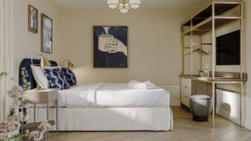 A modern bedroom with a bed, bedside table, lamp, artwork, and a wardrobe.