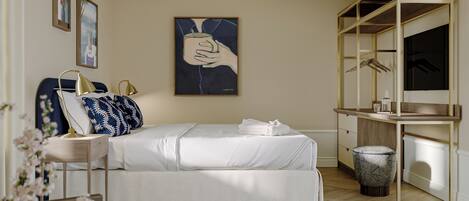 Un dormitorio moderno con cama, mesita de noche, lámpara, obra de arte y armario.