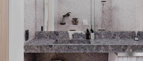 Un baño moderno con encimera de mármol, ducha y perchero.