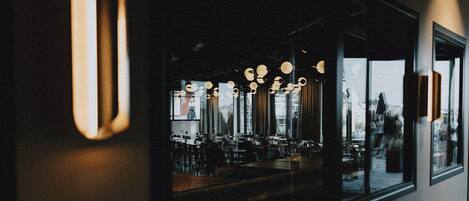 A modern interior with hanging spherical lights, large windows, and a reflective surface.