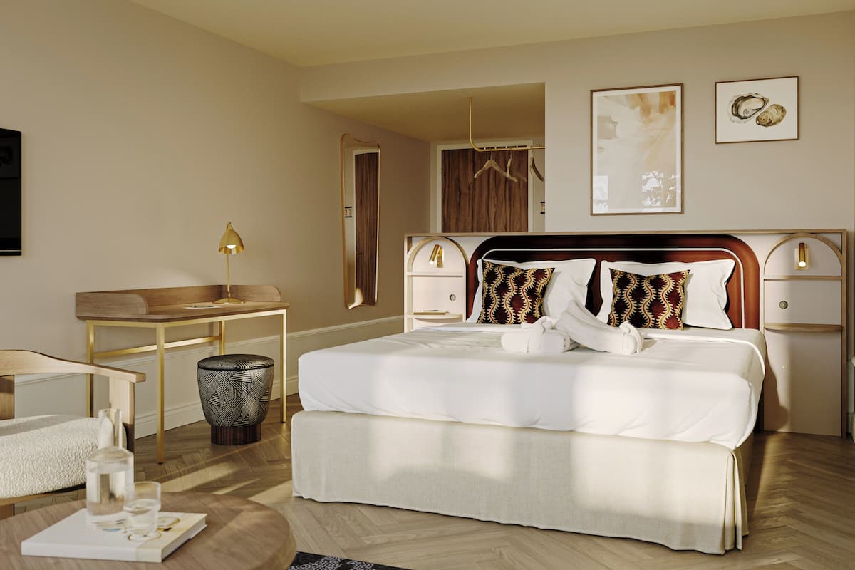 A hotel room with a large bed, bedside tables, a desk, and a chair.