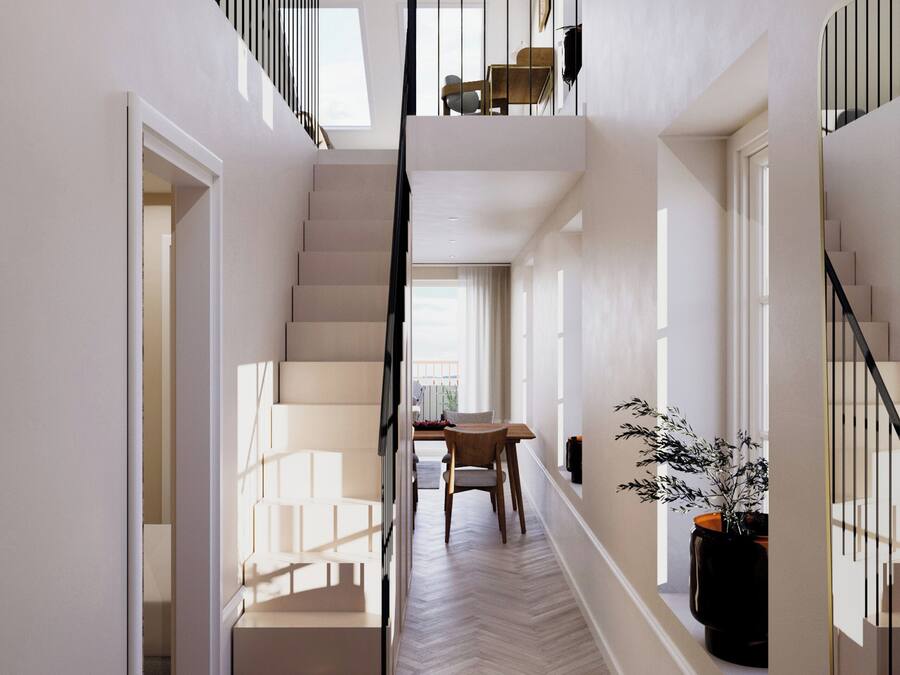 A spacious, well-lit hallway with a herringbone-patterned floor, a staircase with a black railing, and a dining area in the background.
