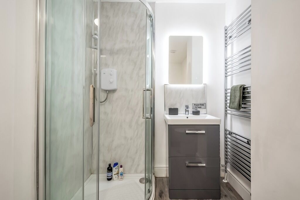 Ein modernes Badezimmer mit Duschkabine aus Glas, Waschtisch mit Spiegel und Handtuchhalter.