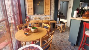 Un comedor con una mesa redonda de madera, sillas y una mesita blanca con camino de mesa estampado.
