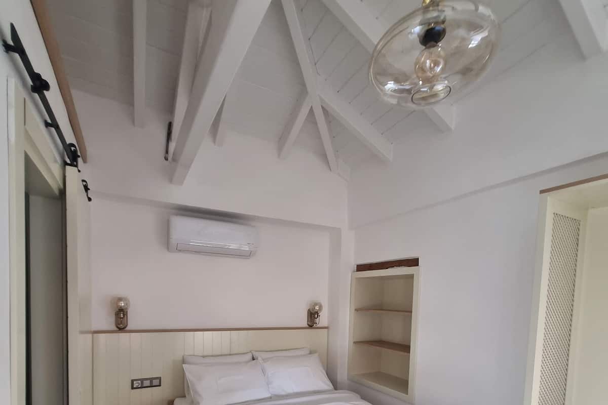 Un dormitorio con cama, mesitas de noche, lámpara colgante y armario.