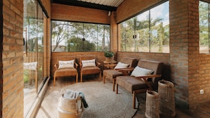 A cozy room with brick walls, large windows, and comfortable seating. - Quinta de Brumado (Óleo)