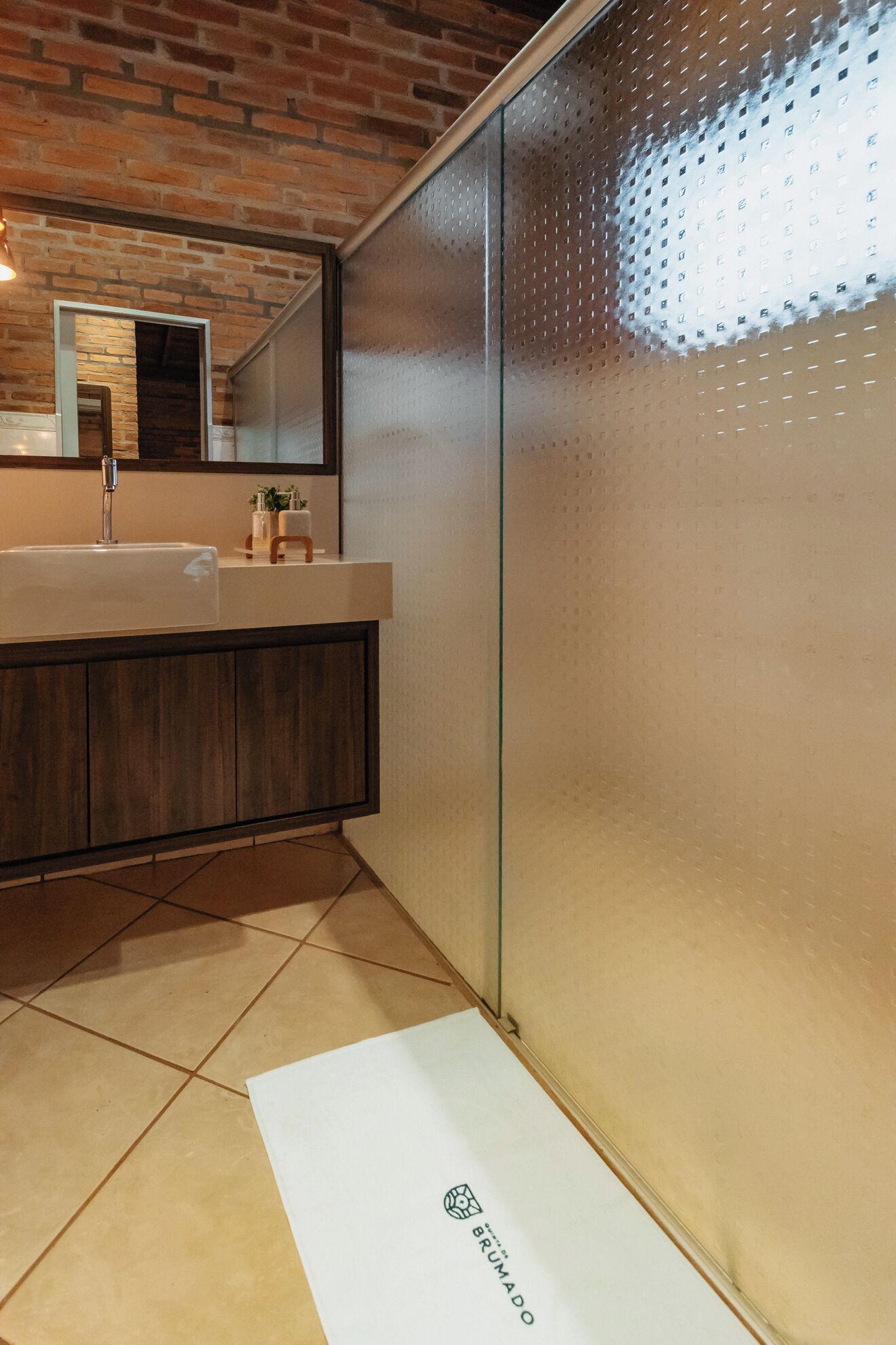 Un baño moderno con cabina de ducha de vidrio, tocador de madera y un espejo grande.