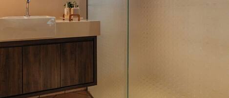 Un baño moderno con cabina de ducha de vidrio, tocador de madera y un espejo grande.