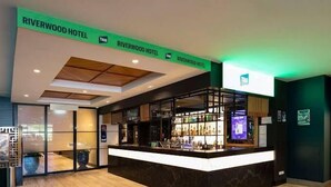 Ein Hotel-Empfangsbereich mit modernem Design, einschließlich einer Rezeption, einer Bar und einem Schild für das Riverwood Hotel.