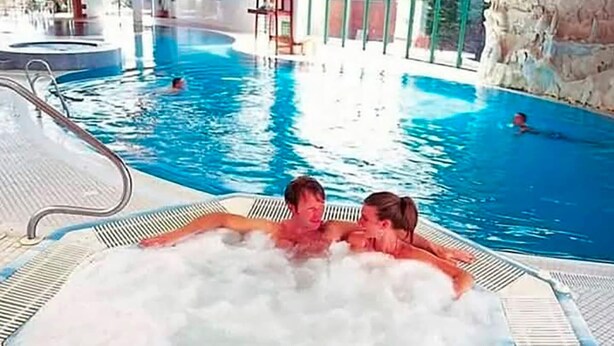 A hot tub with two people sitting in it, surrounded by a swimming pool area. - Shorefield Country Park, 3 Bed,passes Included! (Lymington)