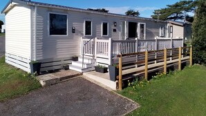 A mobile home with a front porch, a small deck, and a mailbox. - Shorefield Country Park, 3 Bed,passes Included! (Lymington)