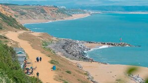 A coastal landscape with a sandy beach, rocky shoreline, and a lighthouse. - Shorefield Country Park, 3 Bed,passes Included! (Lymington)