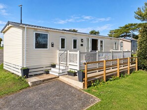 A mobile home with a porch, a wooden fence, and a gravel driveway. - Shorefield 3-bed Lodge, Sleeps 6 w/ Top Reviews (Lymington)