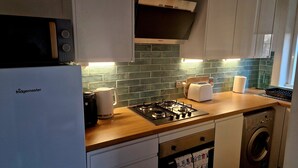 A kitchen with a Bosch gas stove, a Bosch coffee maker, a toaster, and a washing machine. - Troon Beachcombers Apartment (Troon)