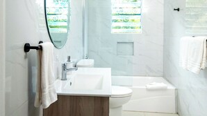 Un baño moderno con un tocador de madera, una bañera independiente y una cabina de ducha de vidrio.