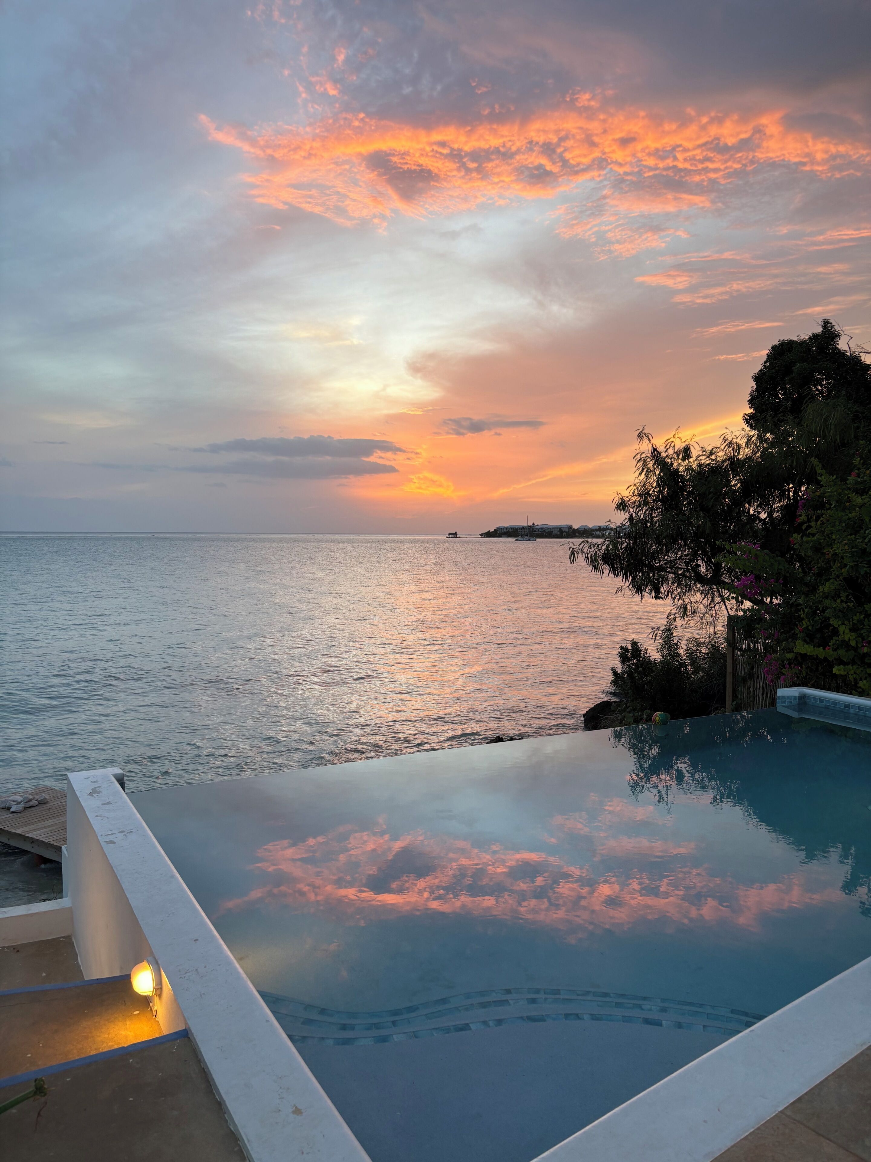 An infinity pool with a view of the sea and a sunset.