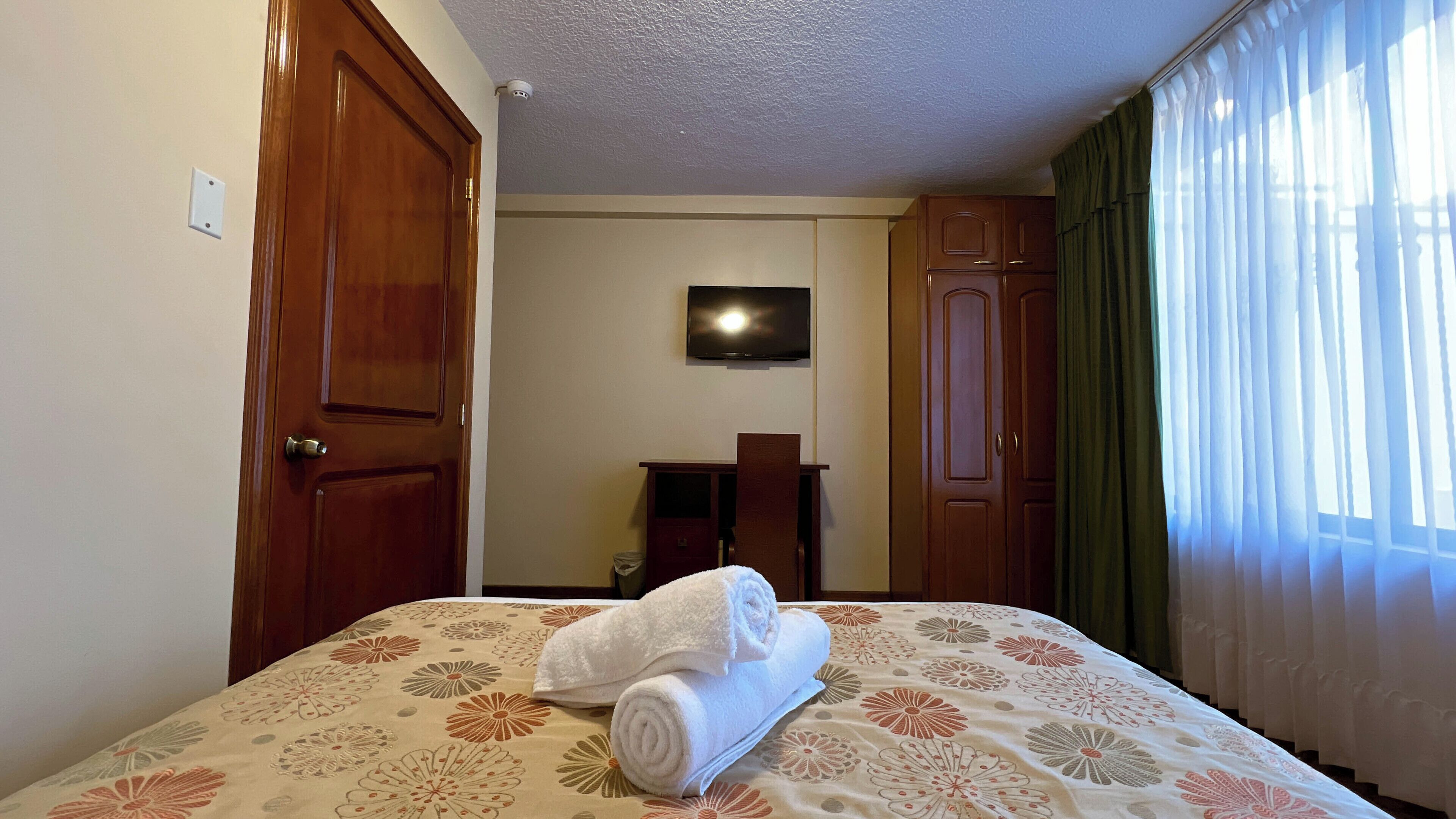 Una habitación de hotel con cama, televisión, escritorio y armario.