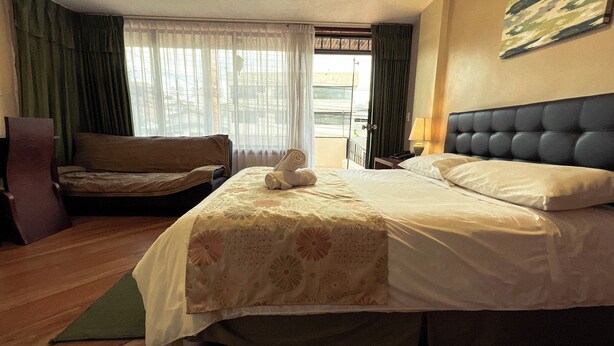 Una camera d'albergo con un letto, una sedia, una scrivania e una finestra con tende.