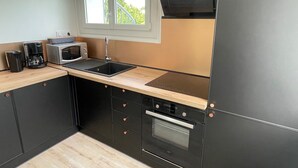 Una cucina moderna con mobili neri, un piano di lavoro in legno, un forno a microonde integrato, una macchina da caffè, un lavello e un forno.