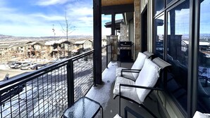 Un balcon donnant sur un paysage enneigé, avec un mur en pierre et un barbecue.