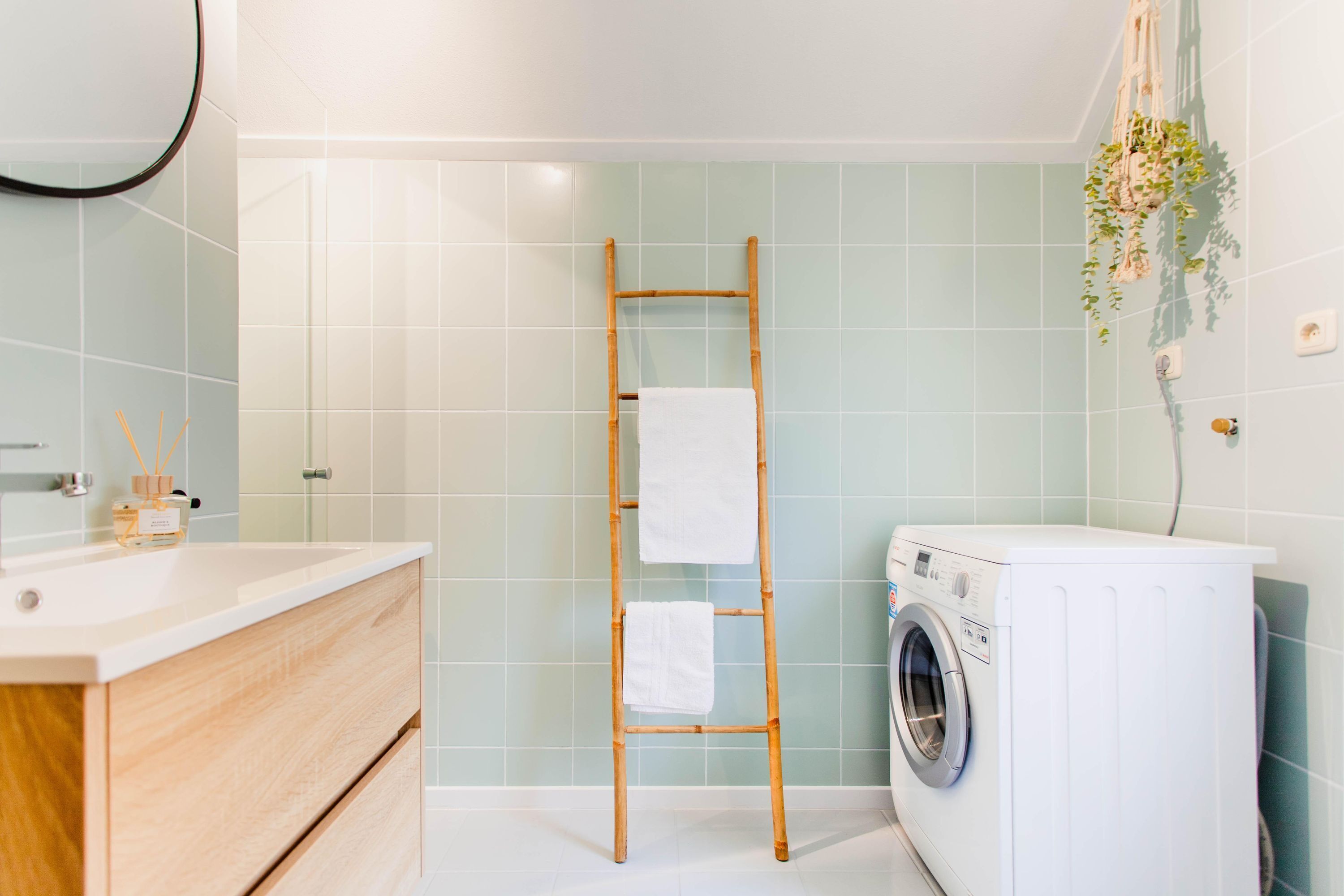 Un bagno con una scala in legno, una lavatrice e un lavandino con specchio.