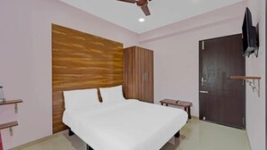 Un dormitorio con cama, armario, ventilador de techo, televisor y una puerta.