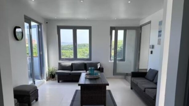 A spacious living area with a sofa set, a coffee table, and large windows offering a view of the outdoors.