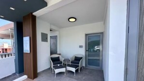 A balcony with two chairs and a small table, a door, and a view of the outside.