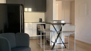 A modern kitchen with a black refrigerator, white cabinets, and a dining area with a table and two chairs.