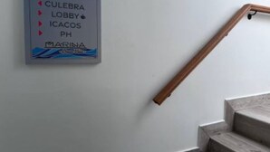 Un escalier avec une rampe en bois et une pancarte sur le mur indiquant les différents lieux : Culebra, hall d’entrée, Icacos, PH et Marina.