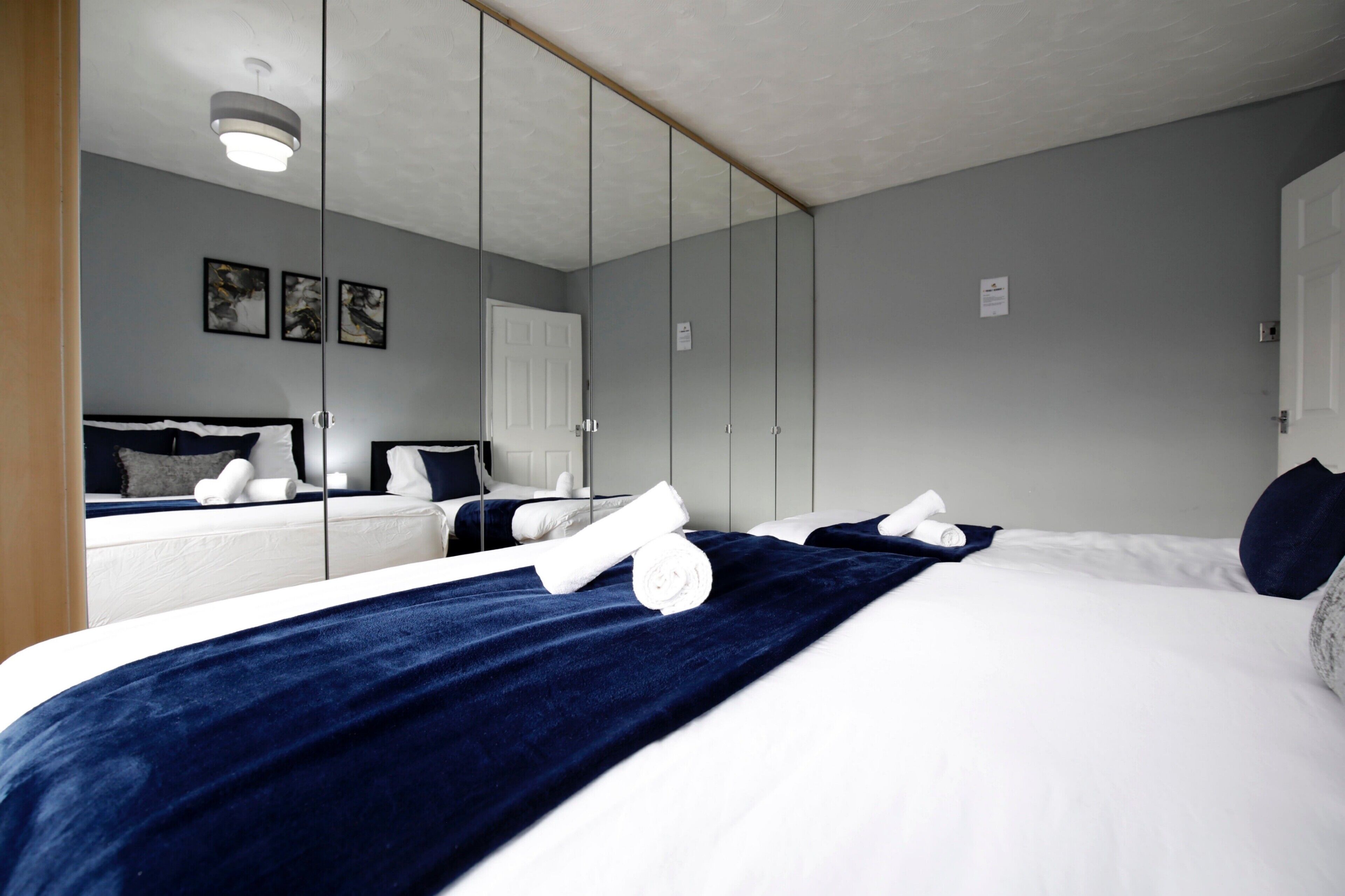 A hotel room with a large bed, a wardrobe, a mirror, and a ceiling light.
