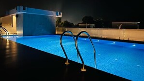 A swimming pool with metal railings and a small building in the background. - UDICHI REGENCY (Bolpur)