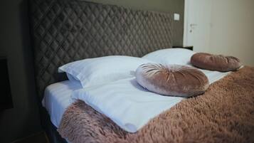 A bed with a quilted headboard, white linens, and two brown pillows.