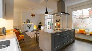 Una cocina moderna con una isla central, iluminación colgante y vistas de la ciudad a través de amplios ventanales.