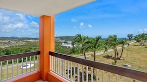 A balcony with a view of a grassy area and palm trees.