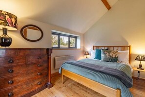 Cozy bedroom with a sloped ceiling, featuring a comfortable bed and a dresser.