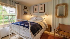 A bedroom with a bed, a chair, a window, and a mirror. - Host & Stay | Haclins Cottage (Stibbard)