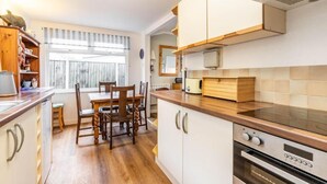 Een moderne keuken met houten kasten, een eettafel met stoelen en een inbouwoven.